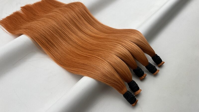 Bundles of straight bulk human hair in colour #ORENGE on a plain background, showing the full sweep down to the bound ends.