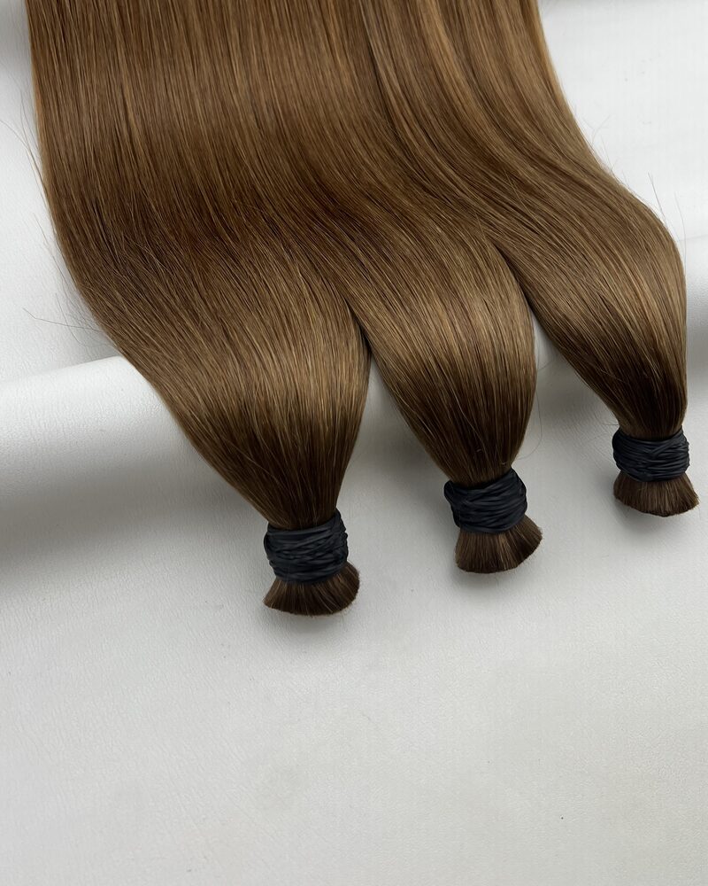 Bundles of straight bulk human hair in colour #7 ALMOND AUBURN on a plain background, photographed from the loose roots down to the bound ends.